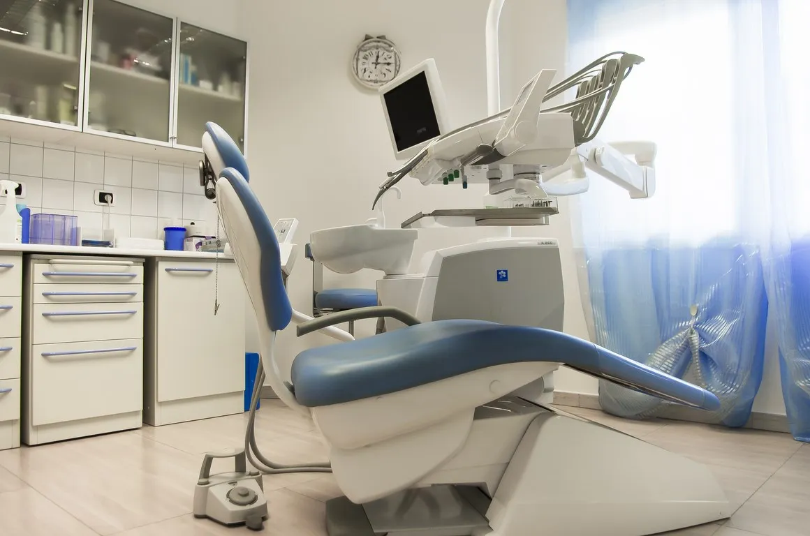 Sala operativa con riunito odontoiatrico blu, monitor e vetrina degli strumenti